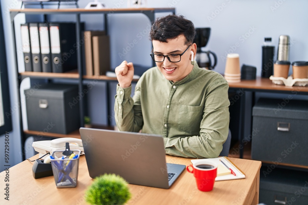Non binary person working at the office wearing glasses screaming proud, celebrating victory and success very excited with raised arm