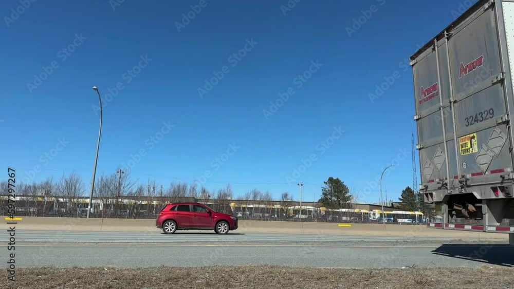 Semi-truck passes a camera on a busy highway exiting Halifax, Canada. big semi trailer with cargo trailer moving on road with cars, low view angle. Semi-truck passes a camera on a busy highway exiting Halifax, Canada. big semi trailer with cargo trailer moving on road with cars, low view angle.