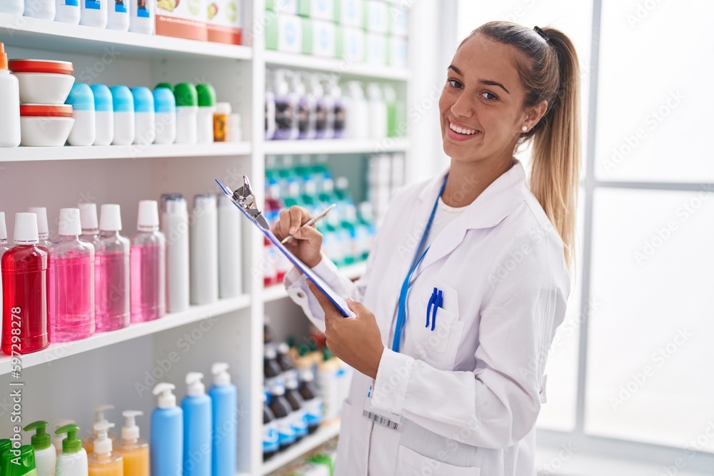 Young beautiful hispanic woman pharmacist smiling confident writing on document at pharmacy