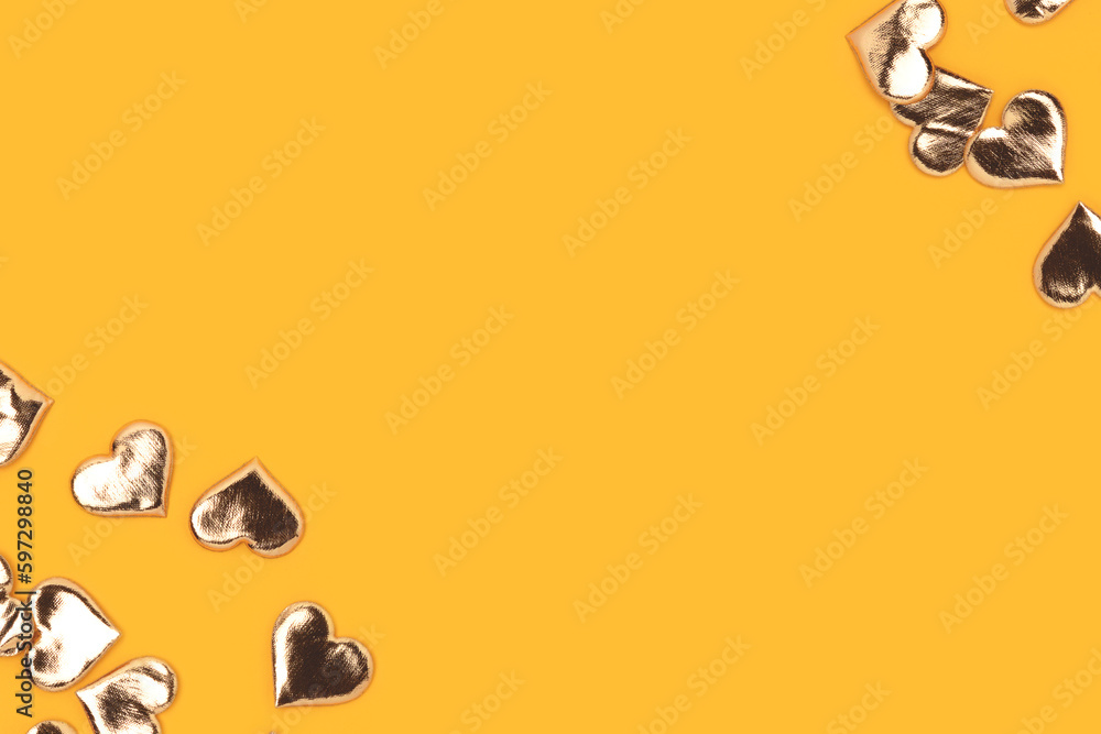 Gold colored hearts confetti scattered on a yellow background. Holidays concept with place for text. Gold colored hearts confetti scattered on a yellow background. Holidays concept with place for text.