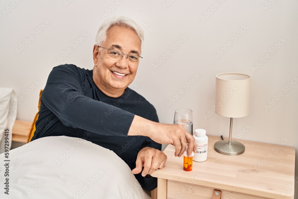Senior man taking pills treatment sitting on bed at bedroom Senior man taking pills treatment sitting on bed at bedroom