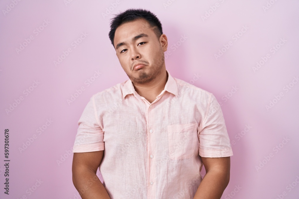 Chinese young man standing over pink background depressed and worry for distress, crying angry and afraid. sad expression. Chinese young man standing over pink background depressed and worry for distress, crying angry and afraid. sad expression.