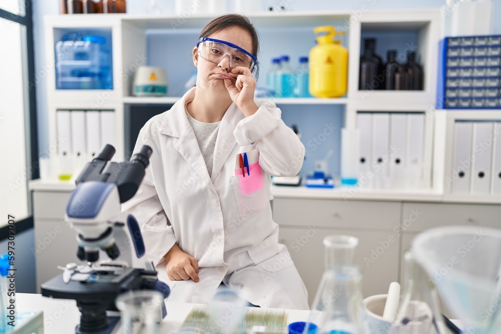 Hispanic girl with down syndrome working at scientist laboratory mouth and lips shut as zip with fingers. secret and silent, taboo talking Hispanic girl with down syndrome working at scientist laboratory mouth and lips shut as zip with fingers. secret and silent, taboo talking