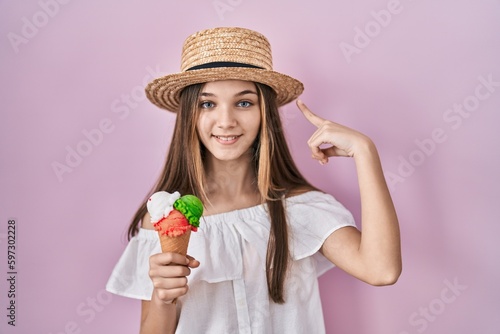 Teenager girl holding ice cream smiling pointing to head with one finger, great idea or thought, good memory