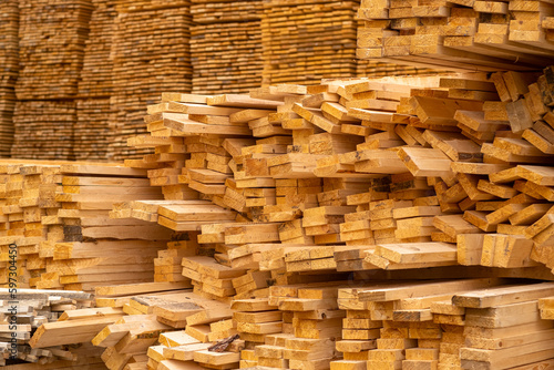 Wooden boards are stored outdoors. Wooden boards, lumber, industrial wood, timber. Pine wood timber stack of natural rough wooden boards on building site.