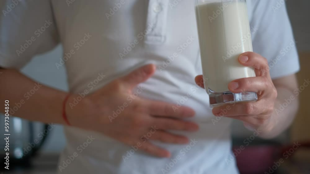 Lactose intolerance. A woman with a glass of milk holds his stomach feeling discomfort Lactose intolerance. A woman with a glass of milk holds his stomach feeling discomfort
