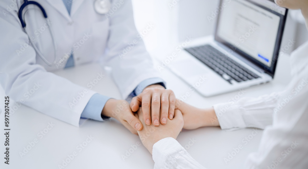 Doctor and patient sitting opposite each other at the table in clinic office. The focus is on female physician's hands reassuring woman, only hands, close up. Medicine concept Doctor and patient sitting opposite each other at the table in clinic office. The focus is on female physician's hands reassuring woman, only hands, close up. Medicine concept