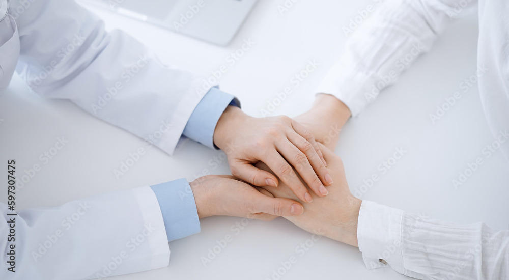Doctor and patient sitting opposite each other at the table in clinic office. The focus is on female physician's hands reassuring woman, only hands, close up. Medicine concept Doctor and patient sitting opposite each other at the table in clinic office. The focus is on female physician's hands reassuring woman, only hands, close up. Medicine concept