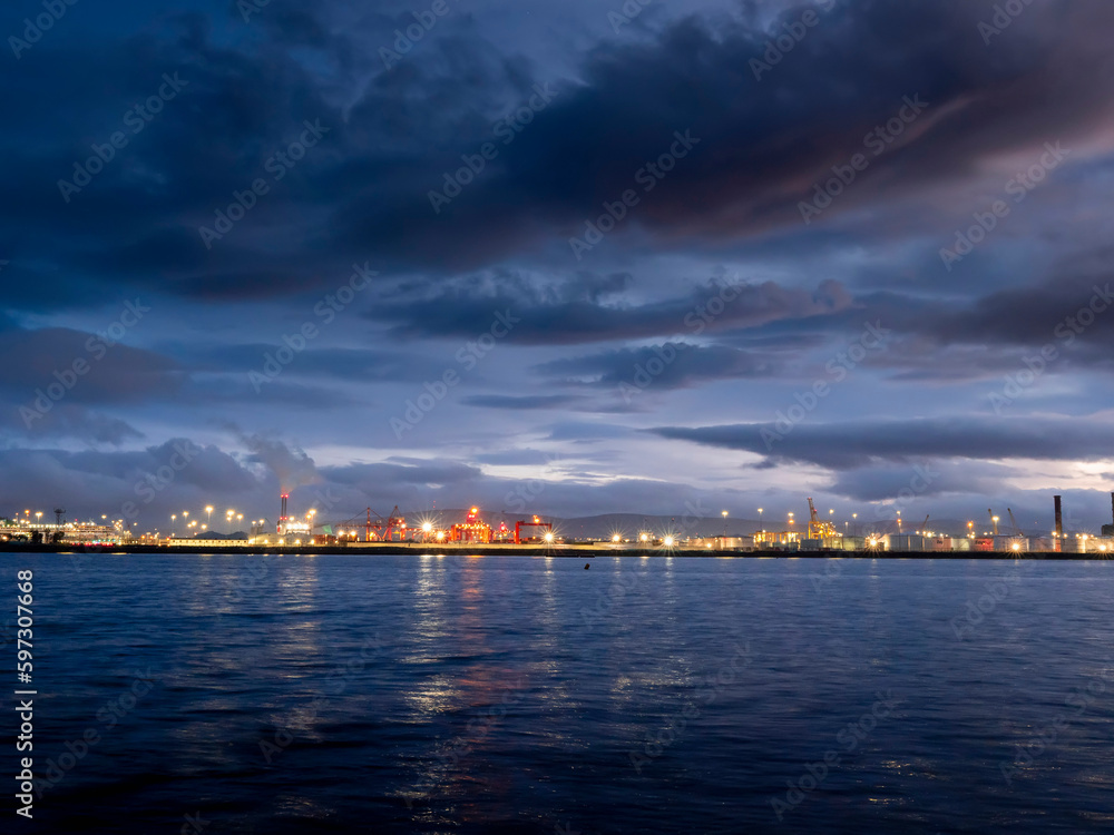 Illuminated dock area of Dublin port at night, Dark dramatic sky. Night shot. Transportation industry, Import and export gate of the country.