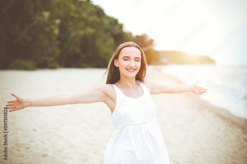 Happy smiling woman in free happiness bliss on ocean beach standing with open hands. Portrait of a multicultural female model in white summer dress enjoying nature Happy smiling woman in free happiness bliss on ocean beach standing with open hands. Portrait of a multicultural female model in white summer dress enjoying nature