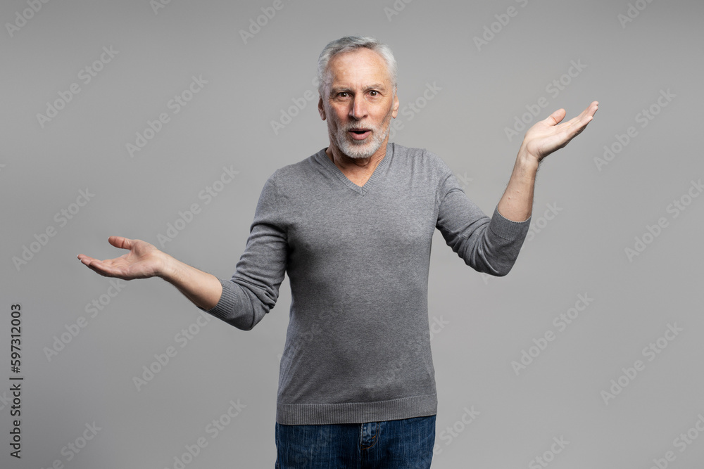 Caucasian handsome surprised gray haired bearded senior man, holding hands palms up, grey background Caucasian handsome surprised gray haired bearded senior man, holding hands palms up, grey background