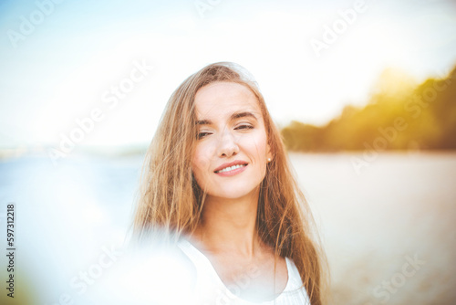 Portrait of a happy smiling woman in free happiness bliss on ocean beach enjoying nature during travel holidays vacation outdoors. View through white blurred flowers © rogerphoto