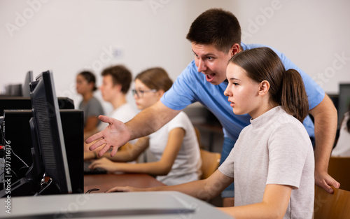 Boy and girl student emotionally reacting while studying at computer in college technology class