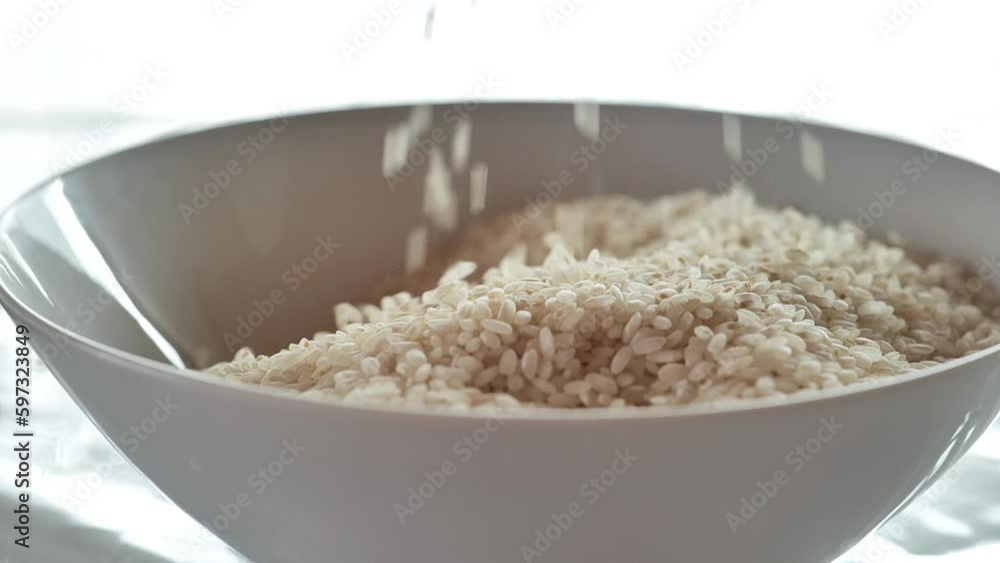 Rice grain white slowly falling into a white plate.Slow motion. carbohydrate food.Long shelf life products. High quality 4k footage