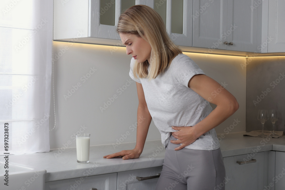 Woman suffering from lactose intolerance in kitchen Woman suffering from lactose intolerance in kitchen