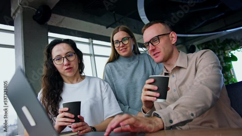 Resilient young millennials working in the office. People look at the laptop and discus data drinking coffee.