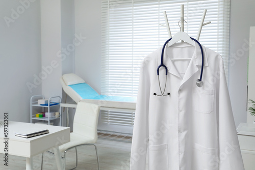 White doctor's gown and stethoscope hanging on rack in clinic. Space for text © New Africa