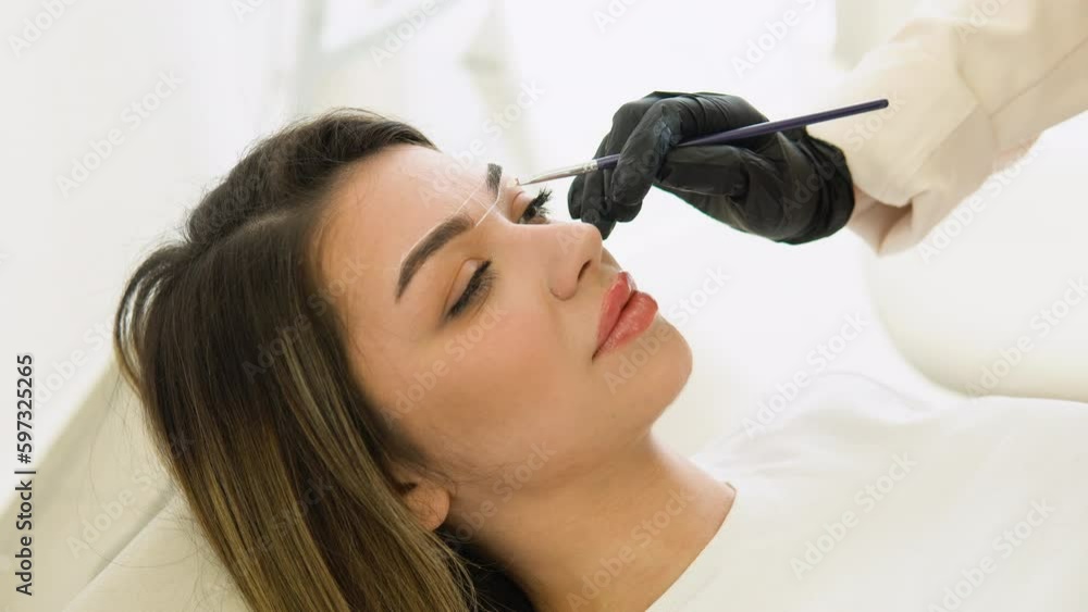 Make-up artist makes markings with white paste for eyebrow tattooing. Permanent makeup tattoo. Professional makeup and skin care cosmetology Make-up artist makes markings with white paste for eyebrow tattooing. Permanent makeup tattoo. Professional makeup and skin care cosmetology