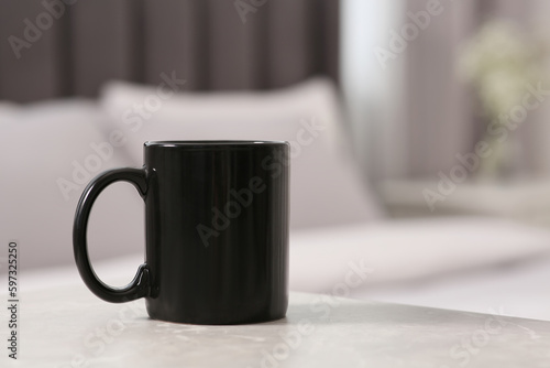 Black ceramic mug on table indoors. Mockup for design