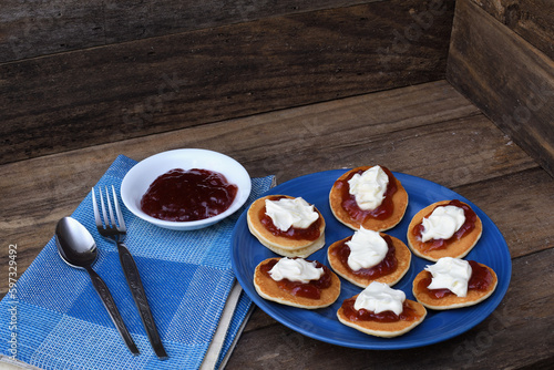 Pikelets Pancakes Battercakes strawberry jam whipped cream blue plate napkin spoon fork rustic wooden setting copy space photo