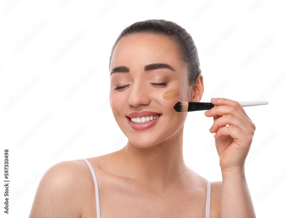 Woman applying foundation on face with brush against white background Woman applying foundation on face with brush against white background