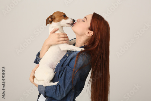 Woman kissing cute Jack Russell Terrier dog on white background