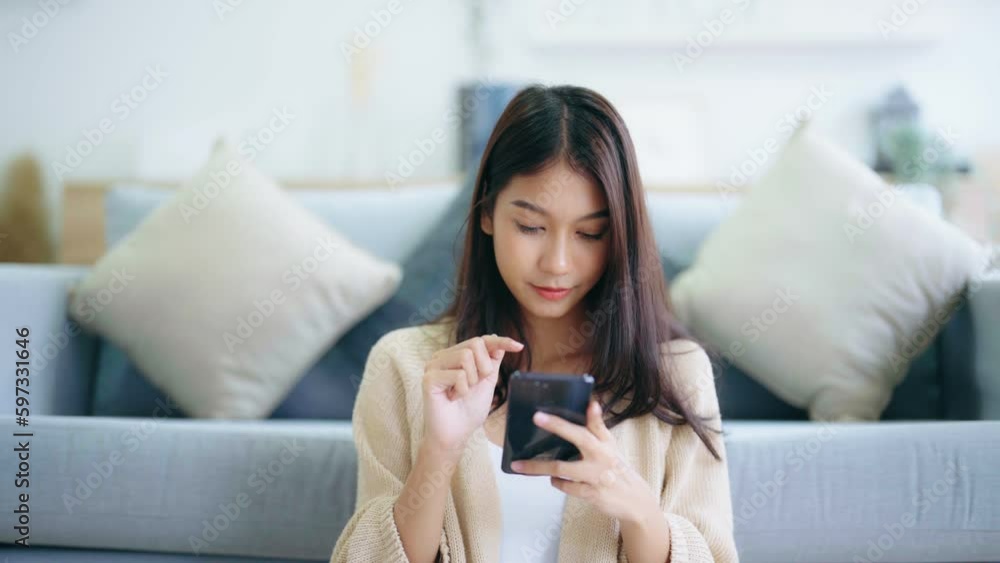 Happy young asian woman relax on comfortable couch at home texting messaging on smartphone, smiling girl use cellphone, chatting online message, shopping online from home Happy young asian woman relax on comfortable couch at home texting messaging on smartphone, smiling girl use cellphone, chatting online message, shopping online from home