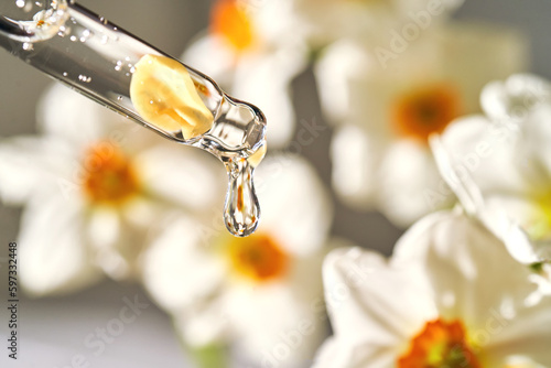 An eyedropper with a cosmetic product on the flower background. © Marevgenna