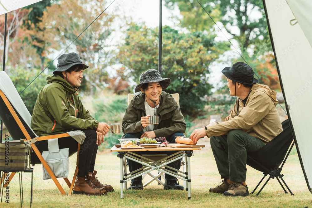 キャンプ飯を仲間と食べるアジア人男性キャンパー
