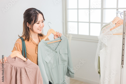 Foto 家・洋服屋・アパレルショップで洋服を選ぶ女性（ファッション・ショッピング）