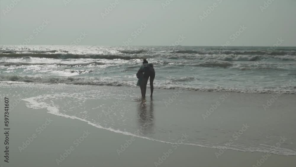 Wide angle shot of mother and child playing in calm waves at Benaulim Beach in Goa Wide angle shot of mother and child playing in calm waves at Benaulim Beach in Goa