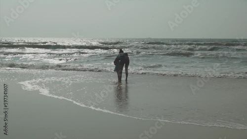 Wide angle shot of mother and child playing in calm waves at Benaulim Beach in Goa photo