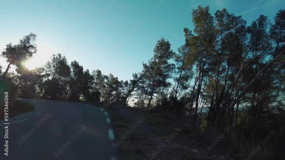 Driving on a mountain road surrounded by vegetation and trees, during the sunrise at early morning, view from the car Driving on a mountain road surrounded by vegetation and trees, during the sunrise at early morning, view from the car