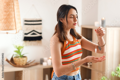 Fototapete Young woman with pendulum at home