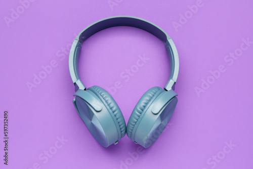 Modern blue headphones on purple background