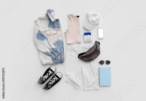 Stylish clothes with accessories, mobile phone and book on white background