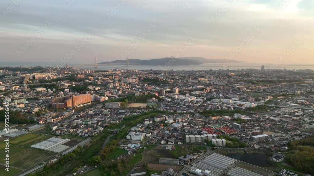 Aerial view of sprawling coastal city with suspension bridge to island at sunset Aerial view of sprawling coastal city with suspension bridge to island at sunset