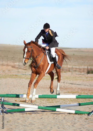 Sport, jump and equestrian with woman on horse for show, competition and performance. Training, derby and health with female jockey on animal in countryside for obstacle, horseback and rider event © Kusjka du Plessis/peopleimages.com