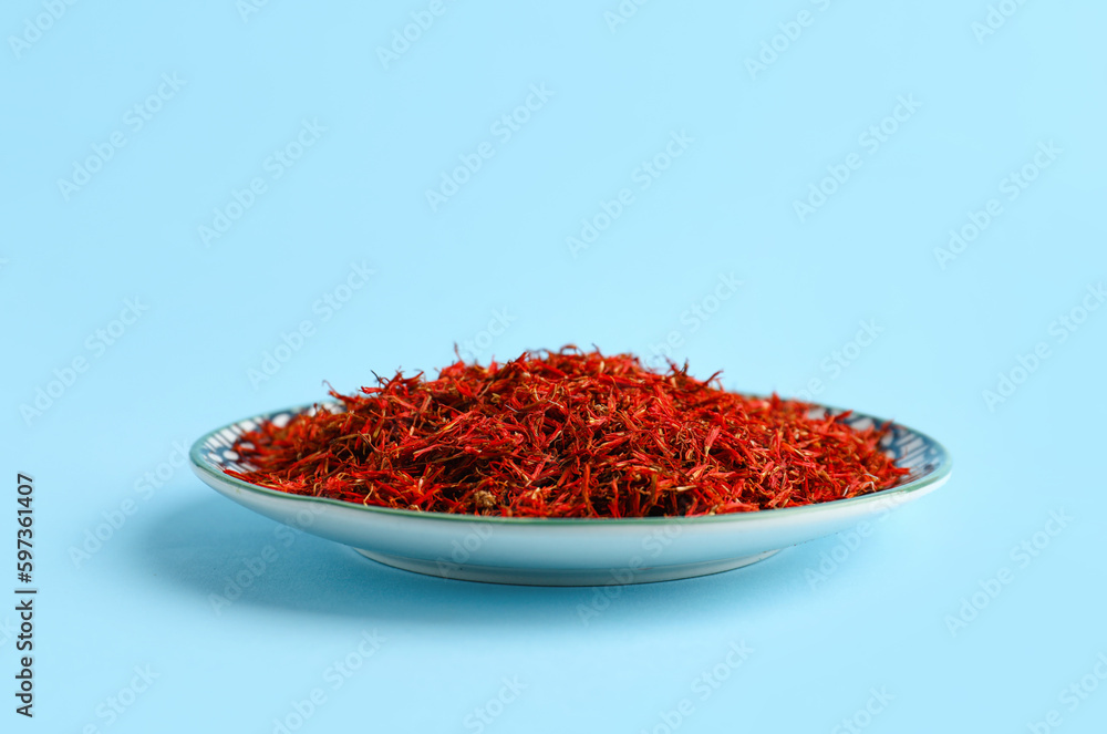 Plate with pile of saffron on blue background Plate with pile of saffron on blue background