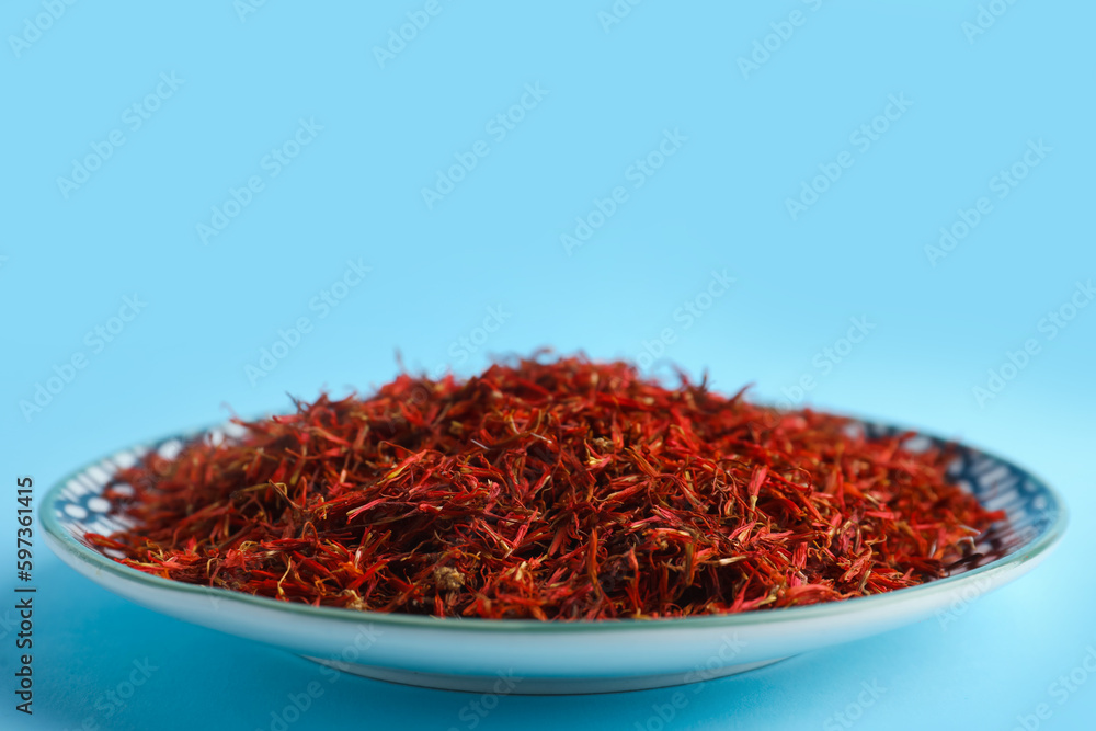 Plate with pile of saffron on blue background Plate with pile of saffron on blue background