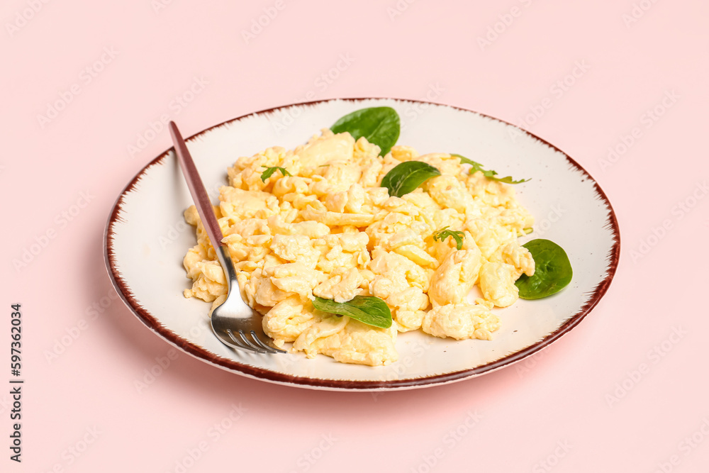Plate of delicious scrambled eggs with herbs on pink background Plate of delicious scrambled eggs with herbs on pink background