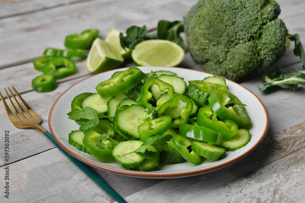 Plate of salad with green vegetables on grey wooden background Plate of salad with green vegetables on grey wooden background
