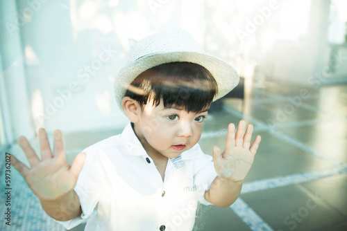 Curious child standing behind the glass and hand pressing on a glass window, looking out window