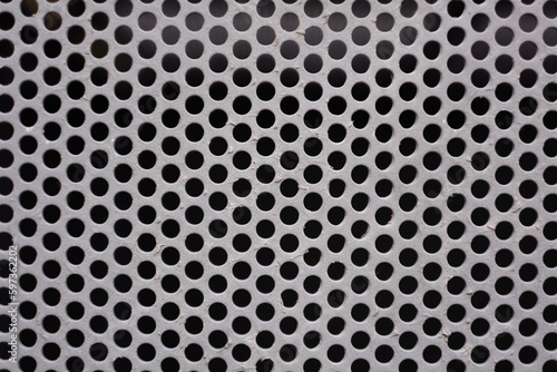 A steel panel has a dizzying pattern of laser-cut holes arranged in a grid.