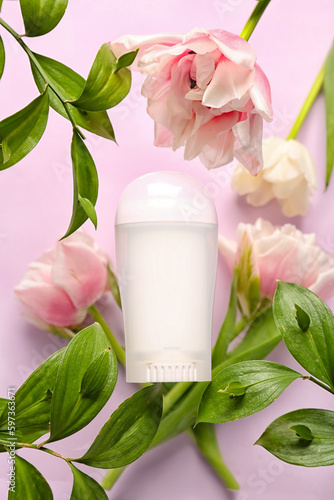 Deodorant bottle, leaves and flowers on pink background