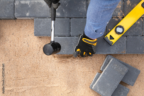 Photo Laying cement pavement on a walkway with a rubber hammer and gloves on a sand
