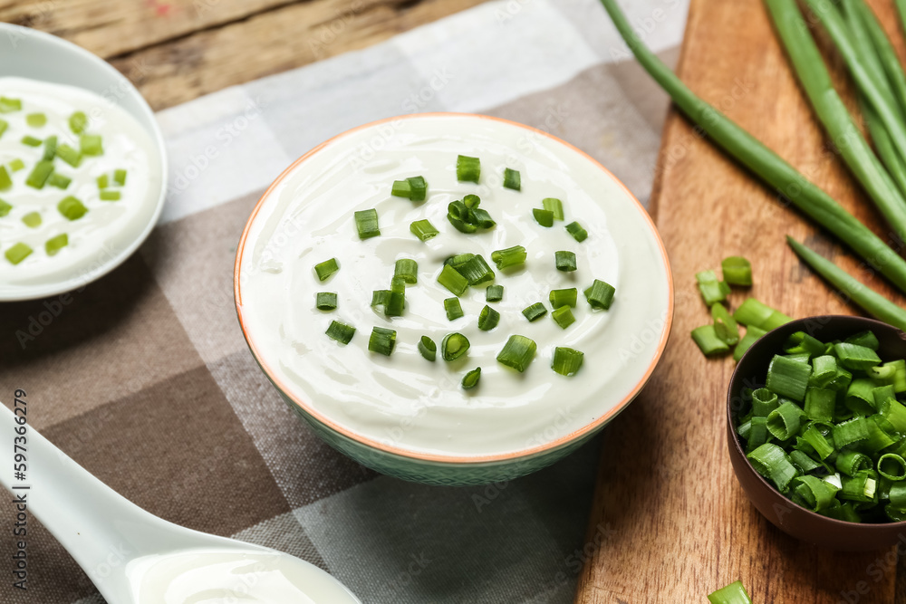Bowl of tasty sour cream with green onion on table Bowl of tasty sour cream with green onion on table
