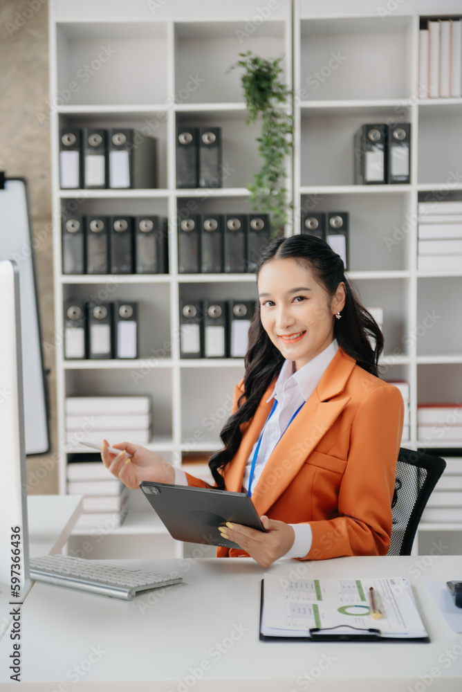 Beautiful Asian business woman typing laptop and tablet Placed at the table at home office Beautiful Asian business woman typing laptop and tablet Placed at the table at home office