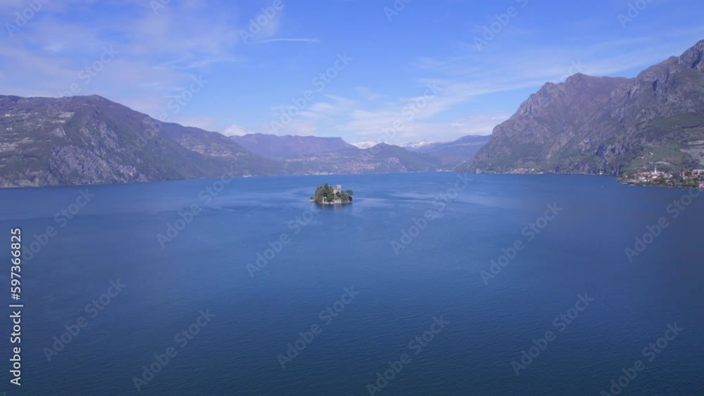 Drone approaching from distant to Loreto small and tiny island in Iseo lake. Italian alps Drone approaching from distant to Loreto small and tiny island in Iseo lake. Italian alps