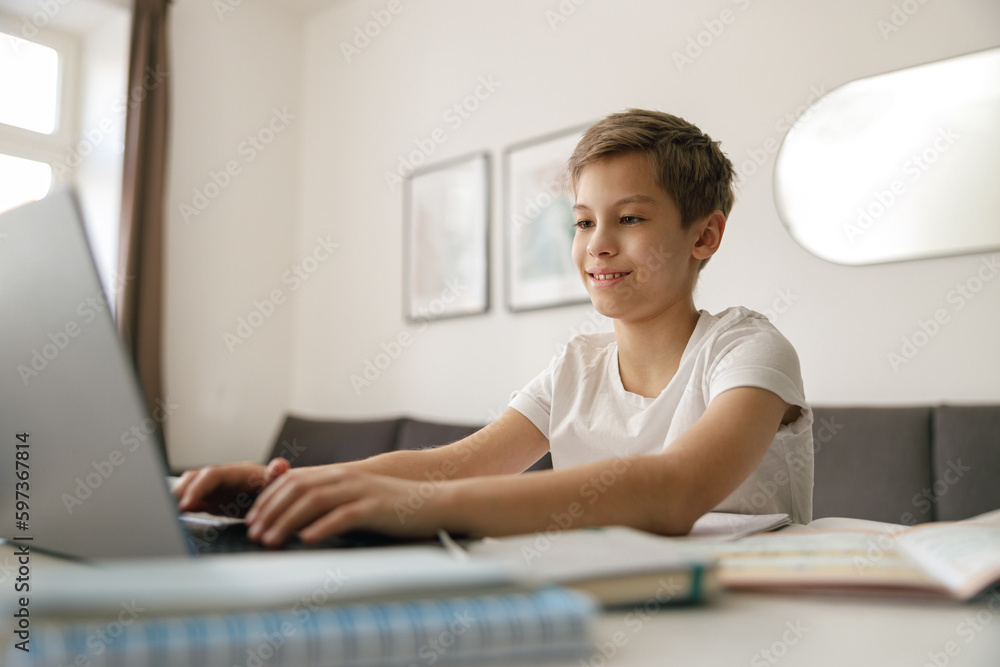 Little kid boy making school homework on laptop while sitting at home in his room Little kid boy making school homework on laptop while sitting at home in his room
